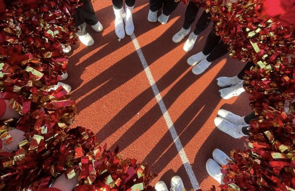 hammarskjold-cheerleading-team-on-field-feet-in-circle-pompoms